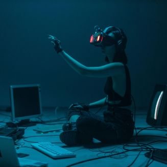Woman immersed in virtual reality, surrounded by tech, in a dimly lit room.